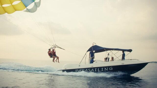 A thrilling parasailing adventure over the open ocean with two people being pulled by a boat. Incredible views and an unforgettable experience for tourists during their holiday.