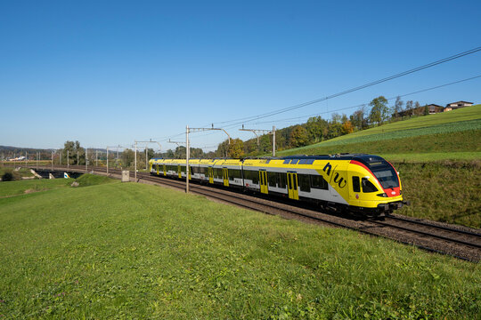 Rotkreuz, Switzerland - October 21, 2023: An SBB passenger train crosses the Reuss Bridge near Rotkreuz under a clear blue sky, capturing smooth Swiss rail travel and everyday mobility.