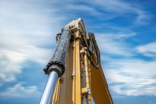 Yellow excavator hydraulic bucket arm, sky and clouds background, nobody