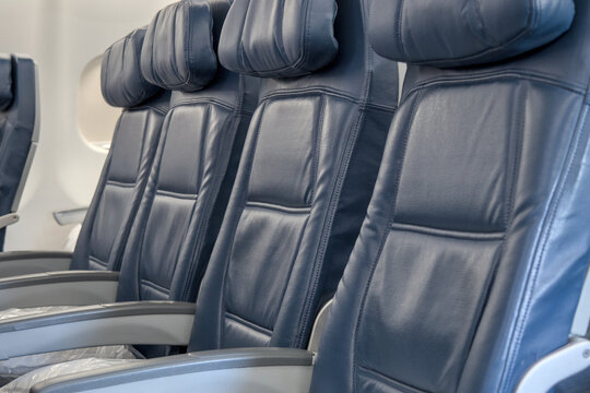 blue empty seats on airplane during takeoff landing (flying plane travel tourism business leisure) overbooked unsold ticket boarding pass row leather seating cushion flight nobody board deplane arm