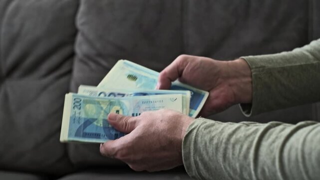 Male hands count Israeli new shekel banknotes in blue color with a 200 NIS denomination in a close-up view