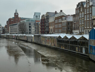 Amsterdam&rsquo;s Bloemenmarkt floating flower market in a rare winter scene. The canal surface is icy, but main waterways rarely freeze solid enough for skating