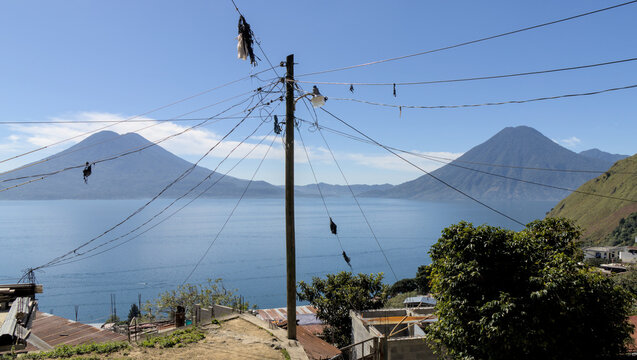 power lines (electric electricity cables) on a pole in santa cruz la laguna lake atitlan guatemala with two volcanoes in the background (volcanic caldera volcano)