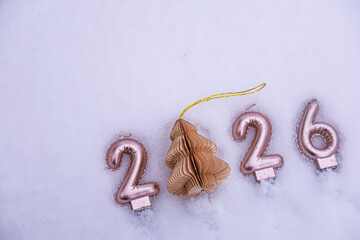 Creative New Year 2026 composition with a paper Christmas tree ornament replacing zero, laid out on snow