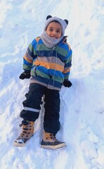 Adorable young boy smiling in fresh winter snow


