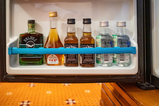 Row of miniature alcohol bottles inside hotel fridge door