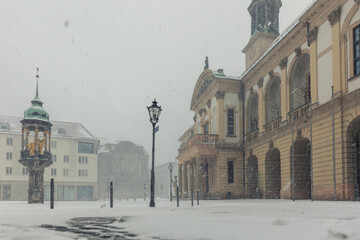 Historic Altermarkt square Magdeburg at heavy snowfall show Rathaus architecture, statues lanterns empty urban space winter storm. Snow covered pavement cold weather dramatic European city atmosphere