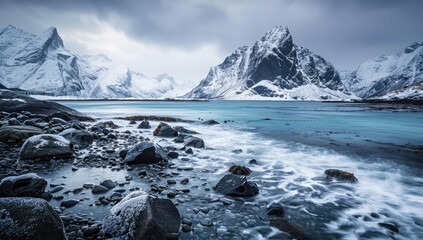 A rugged coastline reveals a snow-covered mountain range and a serene, turquoise sea