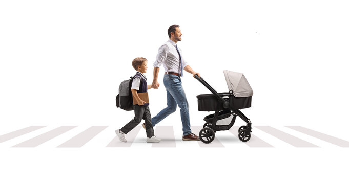 Father walking his son to school while pushing a baby stroller at a crosswalk