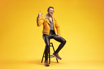 Man in yellow jacket making rock sign