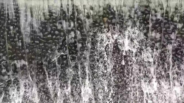 waterfall over dark stones textured water background with splashing stream creating abstract natural pattern ideal for spa wellness design
