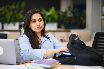 Indian student packing books into backpack studying