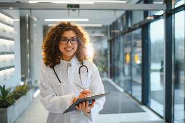 Happy female doctor writing notes in hospital