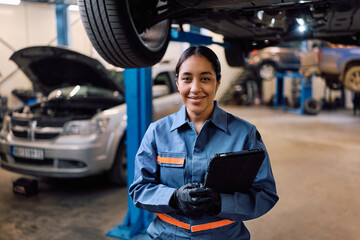 Happy female mechanic in auto repair shop looking at camera.