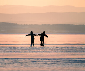 silhouette of people skating on a frozen lake