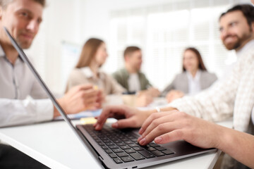 Businesspeople working together at table in office, selective focus