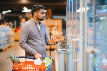 Man buying eggs from supermarket refrigerator