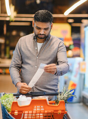 Man calculating grocery expense checking supermarket receipt
