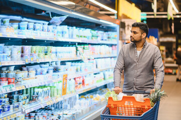 Man shopping for groceries in supermarket dairy aisle