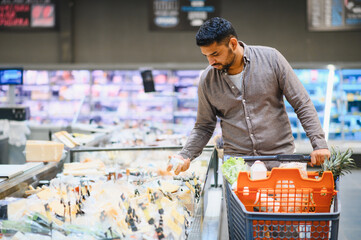 Man shopping for food in grocery store cheese aisle