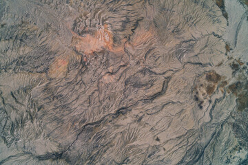 Abstract gray clay texture with orange rust mineral deposits and erosion cracks, quarry background aerial top down view