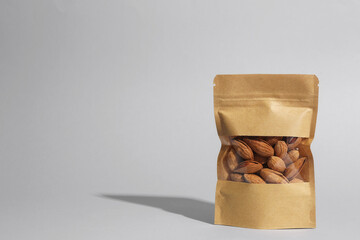 Stand-up pouch with almond nuts on grey background, space for text © New Africa