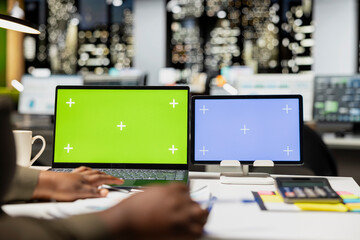 African american CEO at desk uses green screen on laptop and blue screen on tablet, scheduling new meetings and planning the weekly agenda. Business management tasks for a project.