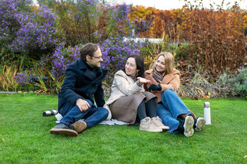 Friends sit together in a garden while sharing stories and enjoying the afternoon sunshine