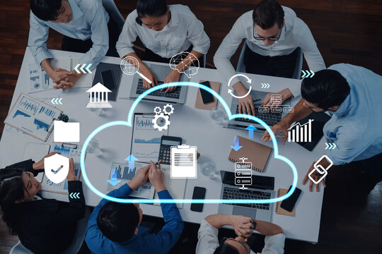 A diverse group of professionals collaborates in a modern office, utilizing cloud technology symbols to enhance discussions on business strategies, data analysis, and innovation. Trope - Powered by Adobe