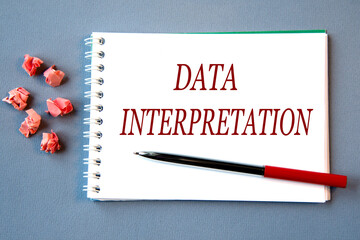 DATA INTERPRETATION - words in a notebook on a gray background with a pen.