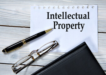 INTELLECTUAL PROPERTY - words in white paper on the background of a diary, glasses and pen