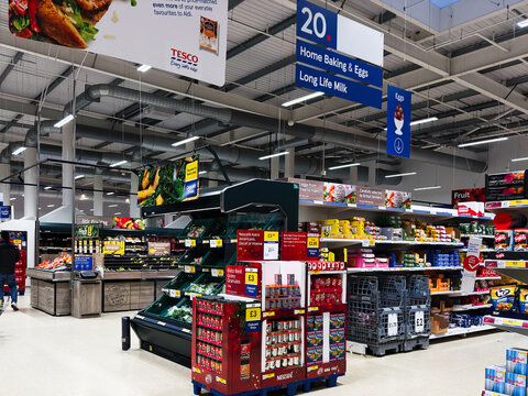Shoppers in a bustling Manchester Tesco supermarket with shelves and colorful signage