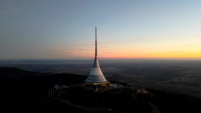 A view of Jested Mountain at sunset shows the transmitter and hotel against the fading light. Located in Liberec, this spot offers stunning landscape views and natural beauty.