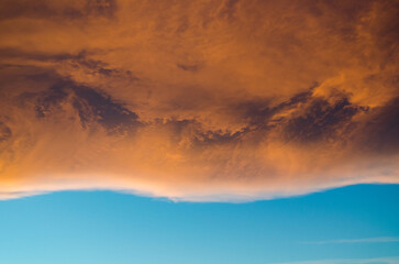 Dramatic Orange and Red Clouds Illuminated by Sun Over Blue Sky