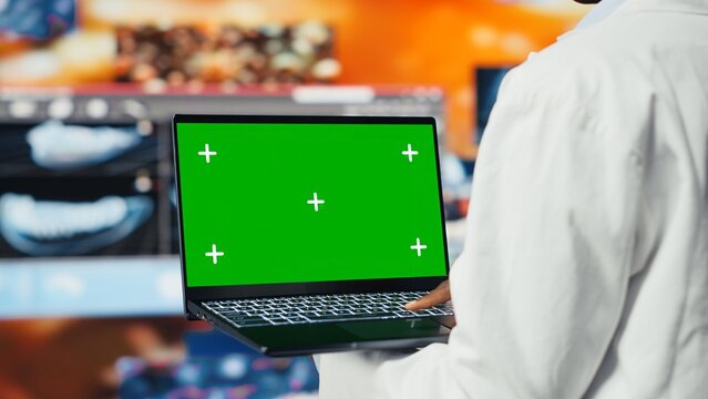 Green screen laptop used by healthcare expert looking at CT scans, MRI data, and lab analytics on videowall. Scientist in medical research lab reading health data with mockup notebook, camera B - Powered by Adobe