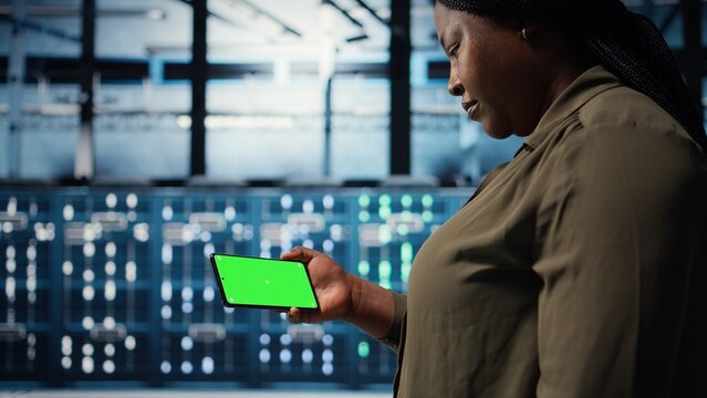 Server hub admin uses isolated screen smartphone to watch video tutorial on how to increase rigs workload capacity. Data center worker following guide on chroma key phone to improve speed, camera A - Powered by Adobe