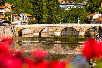 Scenic view of Latin Bridge with textured stone arches crossing Miljacka River in central Sarajevo,...