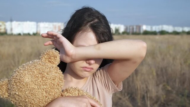 Child with psychological trauma outdoor. A little girl suffer from trauma on her hand with teddy bear outdoor