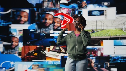 Young woman uses smartphone to do telephone call with mate, discussing online videos. Teenager uses phone to call friend and talk about shared media consumption, colorful multimedia backdrop, camera A