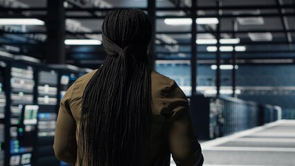 Data center engineer using deep learning on laptop to optimize operations efficiency. IT expert working in server room with specialized hardware accelerating complex AI calculations, camera B