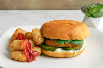 fish fillet sandwich  with a side of tater tots,