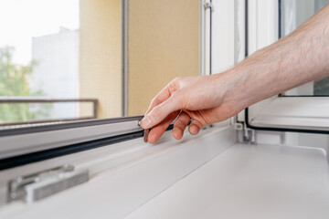 Repairman installs PVC window frame in an apartment for energy efficiency