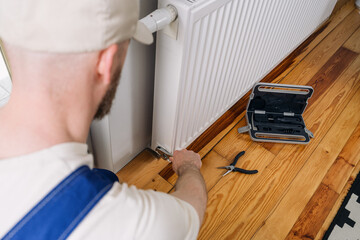 Man performing maintenance on a home heating radiator in a modern interior
