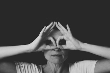 Pensive woman covering eyes with hands against dark background