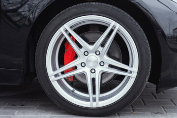 Close-up of a shiny silver alloy wheel featuring multi-spoke design and vibrant red...