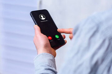 Hand holding modern black smartphone displaying incoming call screen with Accept green and Decline red buttons. Communication decision, mobile connectivity and human-technology interaction.