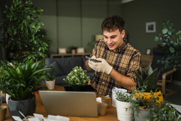 Young man using smart phone while gardening houseplants indoors