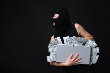 Masked thief with briefcase full of money on black background. Space for text