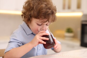 Little boy drinking fresh pomegranate juice at home