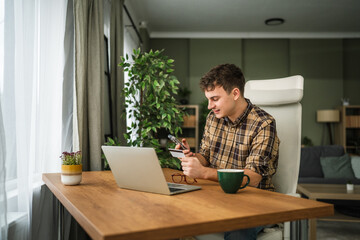 Young man doing online shopping with credit card holding smart phone